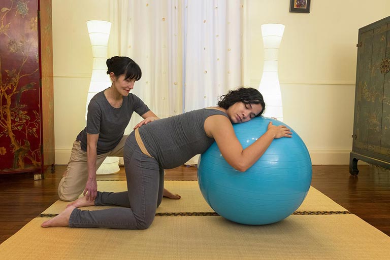 Hélène accompagnant une séance de shiatsu prénatal avec un ballon de confort