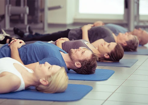 Des participants allongés sur des tapis pendant une séance de relaxation collective
