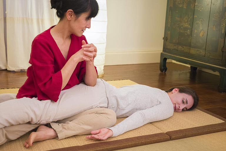 Hélène Scardina pratiquant le shiatsu sur une personne habillée, allongée sur un futon à Angers
